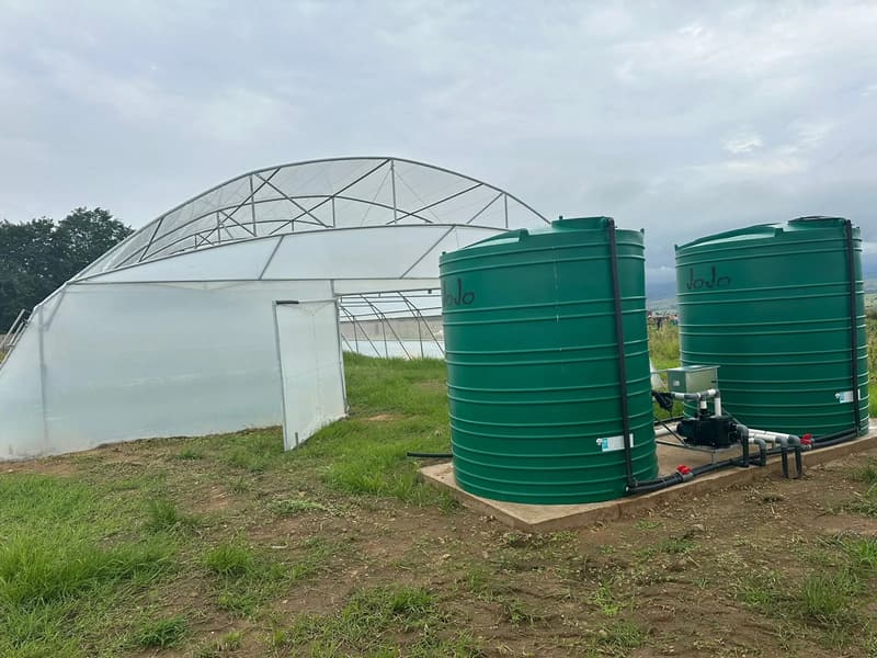Twin JoJo tanks plumbed to a pump station next to a tunnel with its door open