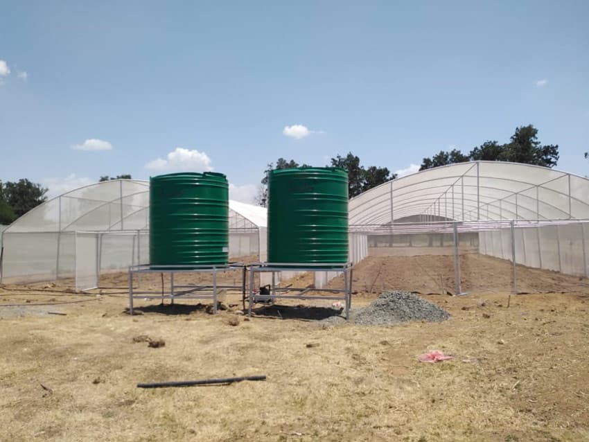 Two green water tanks on raised stands beside the tunnels
